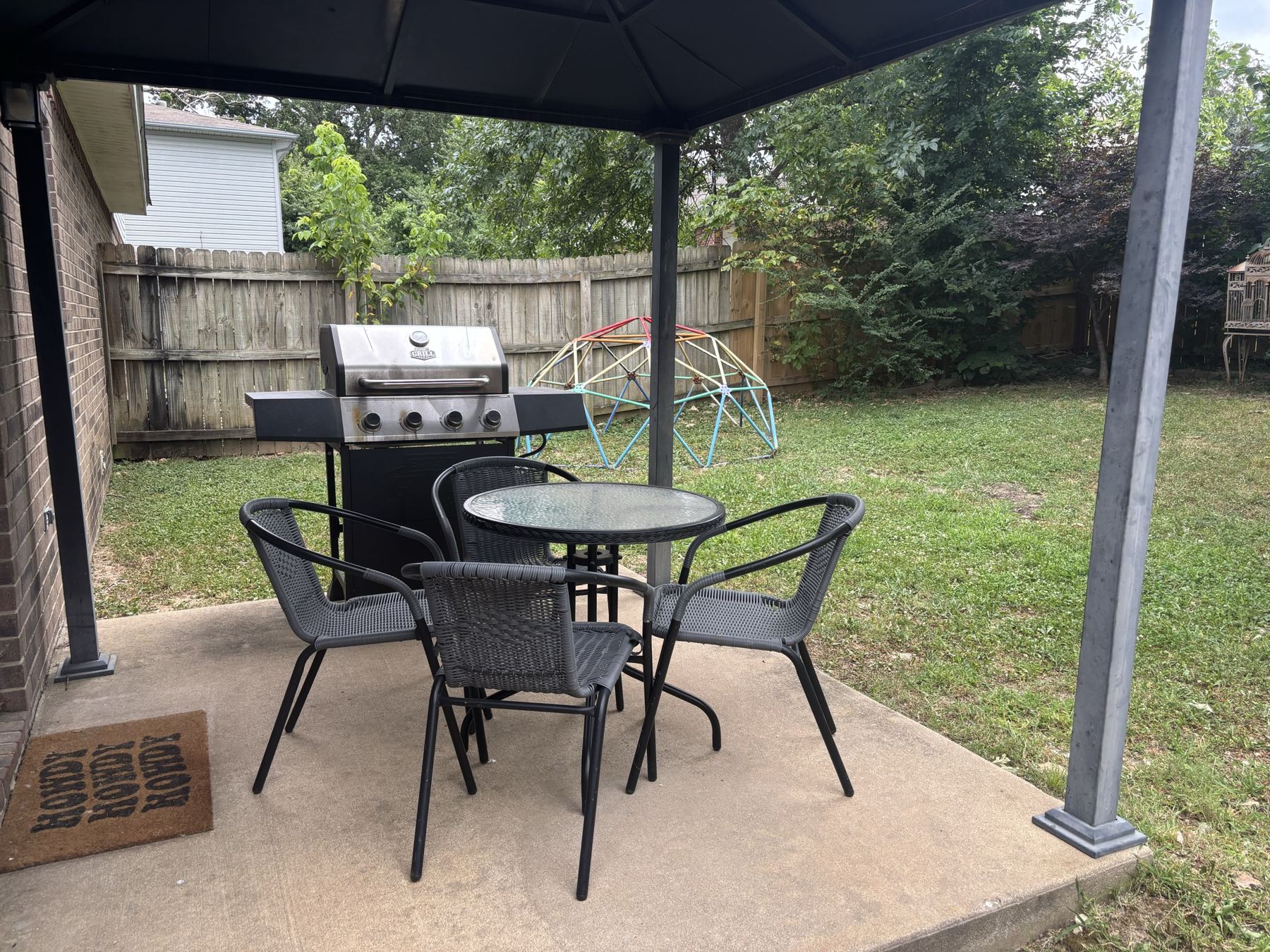 Camellia B covered patio with a grill, looking out over the fenced back yard